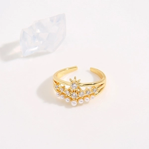 Detailed macro shot of a golden crown ring with shimmering zircons and an elegant pearl