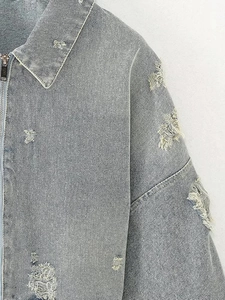 Detail of light blue denim jacket collar and zipper with heavy distressed ripped effects