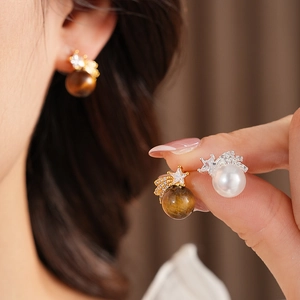 Gros plan détaillé des boucles d'oreilles étoile en œil de tigre et perle