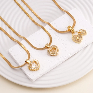 Three gold snake chain necklaces with zircon heart pendants on white display stand