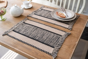 Close-up of cotton woven placemat featuring dark stripes and elegant fringe details