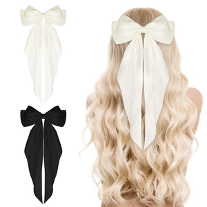 Detail showing white and black satin ribbon bow hair clips on model and as single items