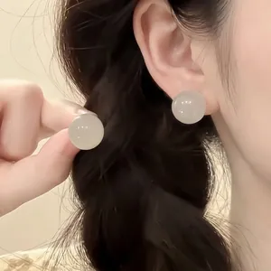 Detailed view of elegant round crystal bead earrings with jade texture on earlobe