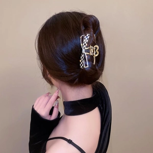 Détail d'une pince à cheveux papillon à damier avec strass sur un chignon brun