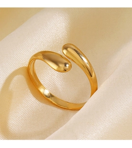 Detailed view of a gold water drop open ring on a soft beige silk fabric background