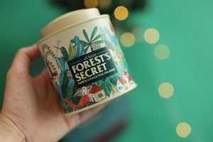 Close-up of a mini tin canister with forest and fox illustrations and a double lid