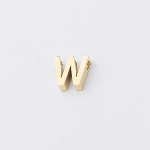 Macro detail of polished gold letter W charm with side hole for jewelry making