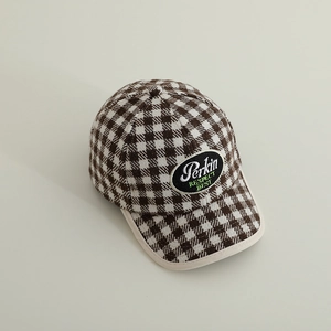 Detail of plaid baseball cap featuring embroidered black patch and white contrast piping