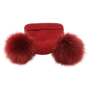 Detailed knit texture of a dark red winter hat featuring two large fluffy pom-poms