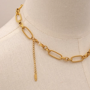 Detail of gold oval link chain necklace with S.STEEL engraved logo tag on the extender