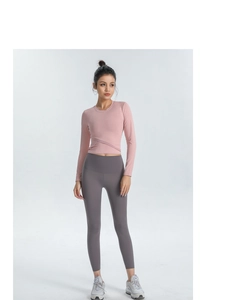 Détail du haut court de yoga rose à manches longues avec taille croisée et legging gris
