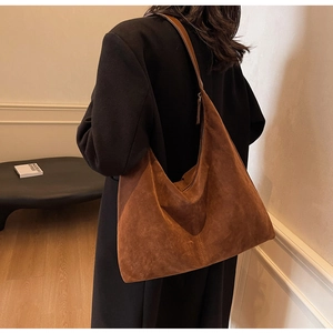 Detail of the high-capacity caramel suede tote bag shown on a shoulder in a stylish setting