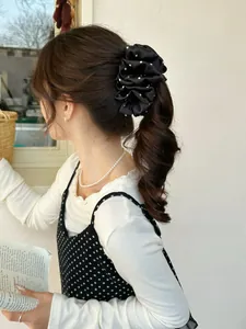 Detail of elegant black and white polka dot satin scrunchie worn on a high ponytail
