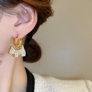 Close-up of gold-plated puppy earrings with sparkling zircon stones worn by a model
