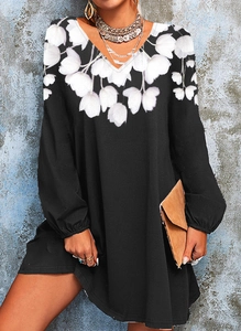 Detailed view of the V-neckline and white floral print on a black long-sleeved dress