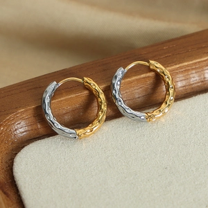 Minimalist hammered gold and silver circular earrings on a wooden jewelry tray