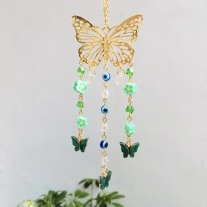 Close-up of golden metal butterfly charm with green beads and evil eye accents