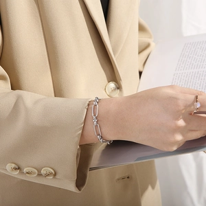 Detail of silver knot chain bracelet styled on model with a minimalist aesthetic