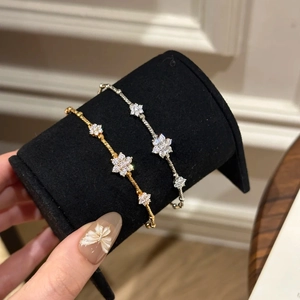 Detail of gold and silver four-leaf clover bracelets with sparkling diamond inlay