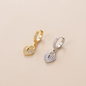 Detailed view of gold and silver heart lock charms with clear zircon on hoop earrings