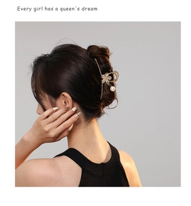 Detail of gold floral hair claw with rhinestone petals, pearl, and long tassels