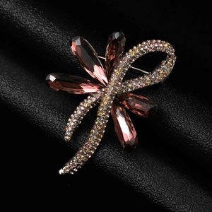 Macro shot of exquisite dragonfly brooch with pink crystals on black leather texture