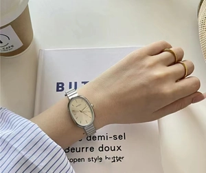 Close-up of elegant oval dial watch and silver strap set in a lifestyle aesthetic