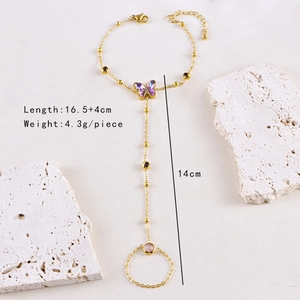 Detailed shot of golden butterfly slave bracelet with purple wings and pink gemstone ring