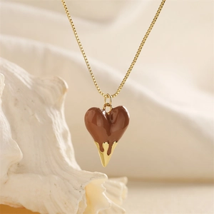 Macro detail of brown heart pendant with gold drip effect on a fine gold-colored box chain