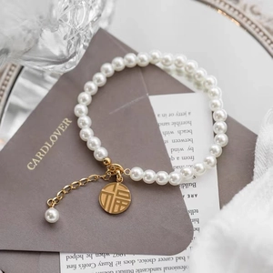 Detailed shot of pearl bracelet with gold Fu character pendant on vintage backdrop