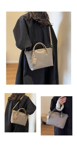 Detail showing grey oxford tote bag with top handles, adjustable strap and mini pouch charm
