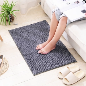 Gray chenille bath mat on wooden floor with a person standing on soft textured surface