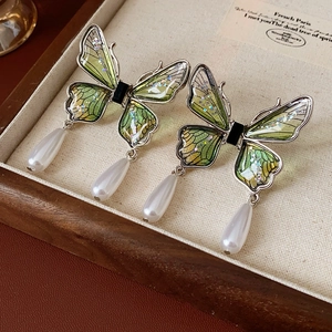 Detail of green butterfly earrings with silver glitter wings and drop pearl accents