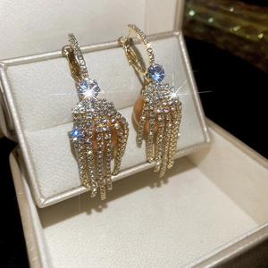 Detail of gold tassel earrings with sparkling crystals and a champagne pearl drop