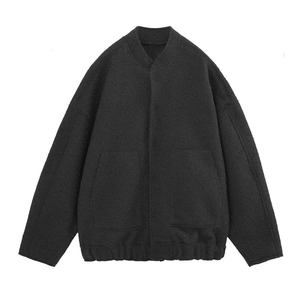 Detail of dark charcoal bomber jacket showing textured wool fabric and drop shoulder design