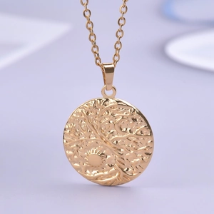 Macro shot of gold tree of life embossed pendant on stainless steel o-chain necklace