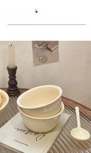 Close-up of cream-colored reinforced ceramic bowls and matching spoon on a book