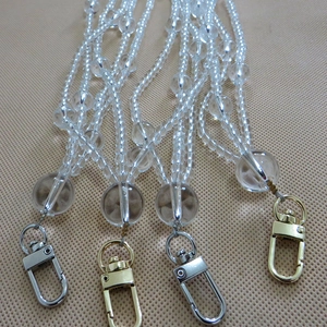 Detail view of transparent beaded handbag straps with gold and silver metal lobster clasps