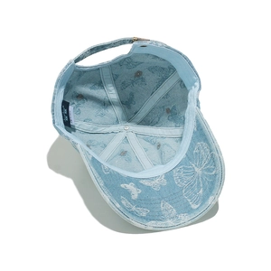 Detail view of denim baseball cap interior with butterfly embroidery and metal buckle