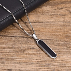 Macro shot of silver stainless steel geometric pendant with black inlay and cable chain