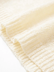 Macro shot of cream knit fabric texture with ribbed edge details and soft fibers
