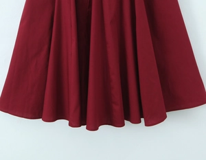 Détail de l'ourlet de robe plissée rouge foncé montrant les coutures et la texture du tissu