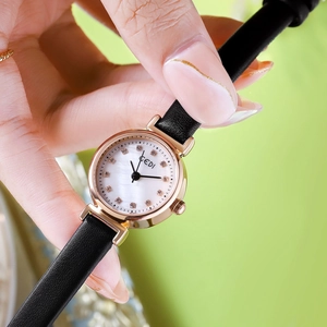 Elegant gold watch with black leather strap and pearl dial featuring crystal markers