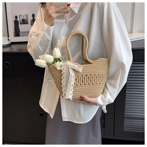 Close-up of straw woven bucket bag with elegant white lace bow detail and texture