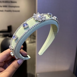 Detail of light green padded satin headband with flower crystal and pearl embellishment