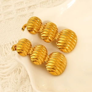 Minimalist gold plated stainless steel oval earrings with vintage textured beads on a tray