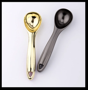 Close-up of gold and dark grey metallic ice cream scoops with a polished finish