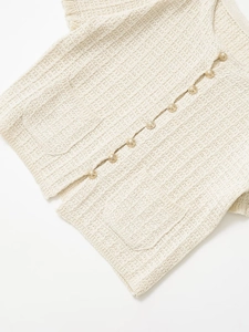 Close-up of cream knit texture and elegant gold buttons on the short sleeve cardigan