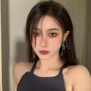 Silver bow-shaped ribbon earrings showing fluid metallic texture on female model
