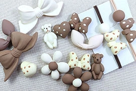 Detailed set of teddy bear and heart hair clips and ties on soft beige fabric background